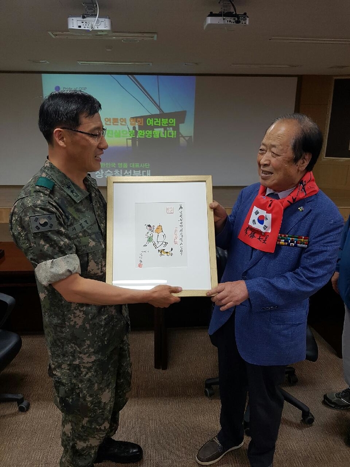 박기병 6.25참전 언론인회 회장(오른쪽)이 서정열 사단장에게 ‘고바우 영감’만화가 김성환 화백의 그림을 선물로 전해주고 있다.