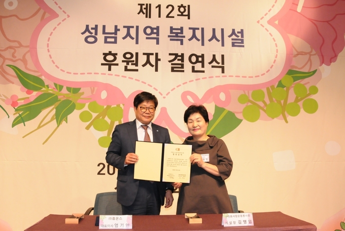 지난 16일 성남상공회의소에서 개최한 ‘제12회 성남지역 복지시설 후원자 결연식’에서 휴온스 엄기안 대표(좌측)와 효사랑운동봉사회 김맹임 시설장(우측)이 대표로 결연 증서에 서명하고 기념촬영.