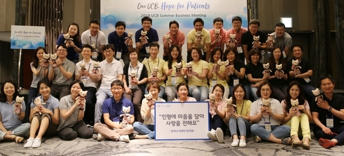 한국UCB제약 임직원들이 영유아 정서지원을 위해 직접 만든 친환경 인형을 들고 기념 촬영.