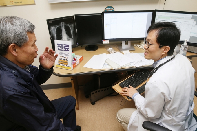 서울아산병원 호흡기내과 이세원 교수가 택시기사의 폐기능 검사와 흉부 X-선 검사를 확인하며 진료상담을 하고 있다.