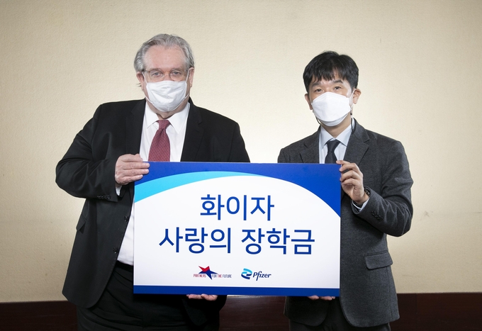 한국화이자제약 오동욱 대표이사 사장(우)이 미래의동반자재단 제프리 존스 이사장에게 ‘화이자 사랑의 장학금’을 전달하고 있다.
