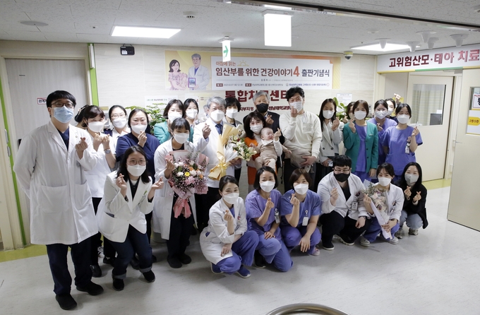 전남대학교병원 고위험산모·신생아통합치료센터 김윤하 센터장이 지난 7일 오후 센터 앞에서 임산부를 위한 의학지침서 ‘아침에 읽는 임산부를 위한 건강이야기’ 발간을 기념한 출판기념식을 열고 의료진 및 치료했던 환자들과 함께 단체사진을 촬영하고 있다.