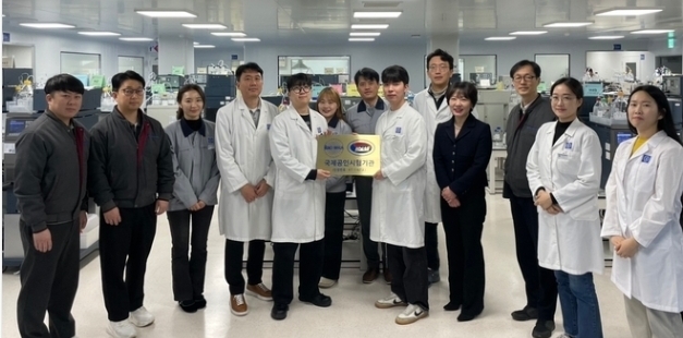 종근당 천안공장에서 황주영 이사(우측 세번째)와 임나영 이사(우측 네번째)를 비롯한 임직원들이 국제공인시험기관 인증마크를 들고 기념 촬영을 하고 있다.